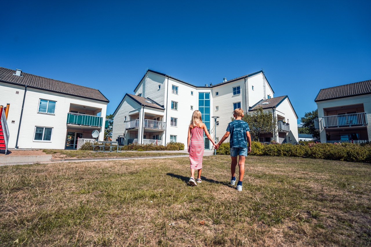 två barn håller hand vid ett bostadsområde